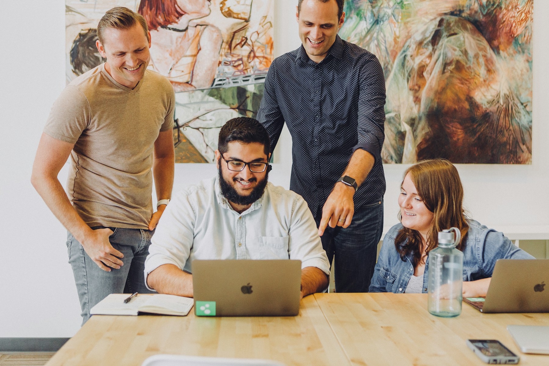 Smiling professionals reviewing work together around a laptop